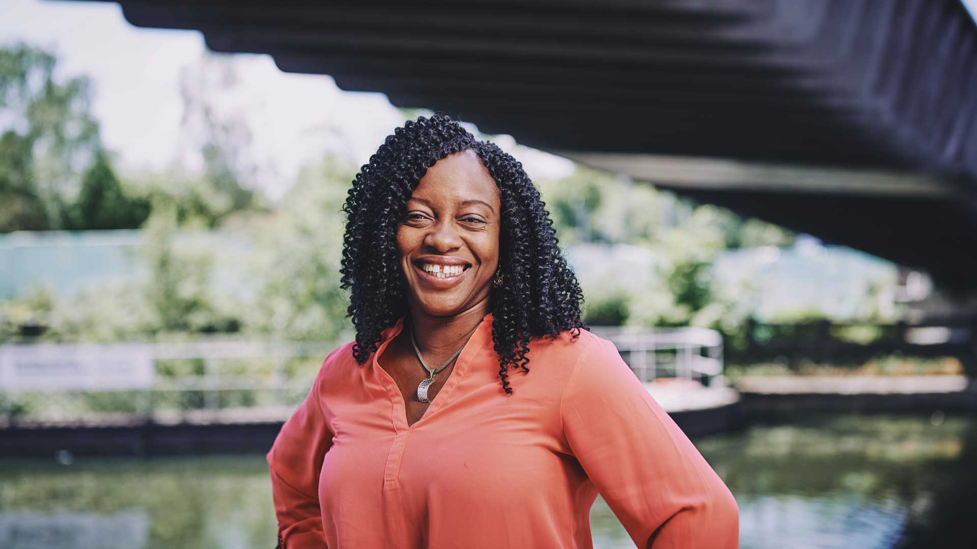 woman standing on a bridge smiling with water in the background