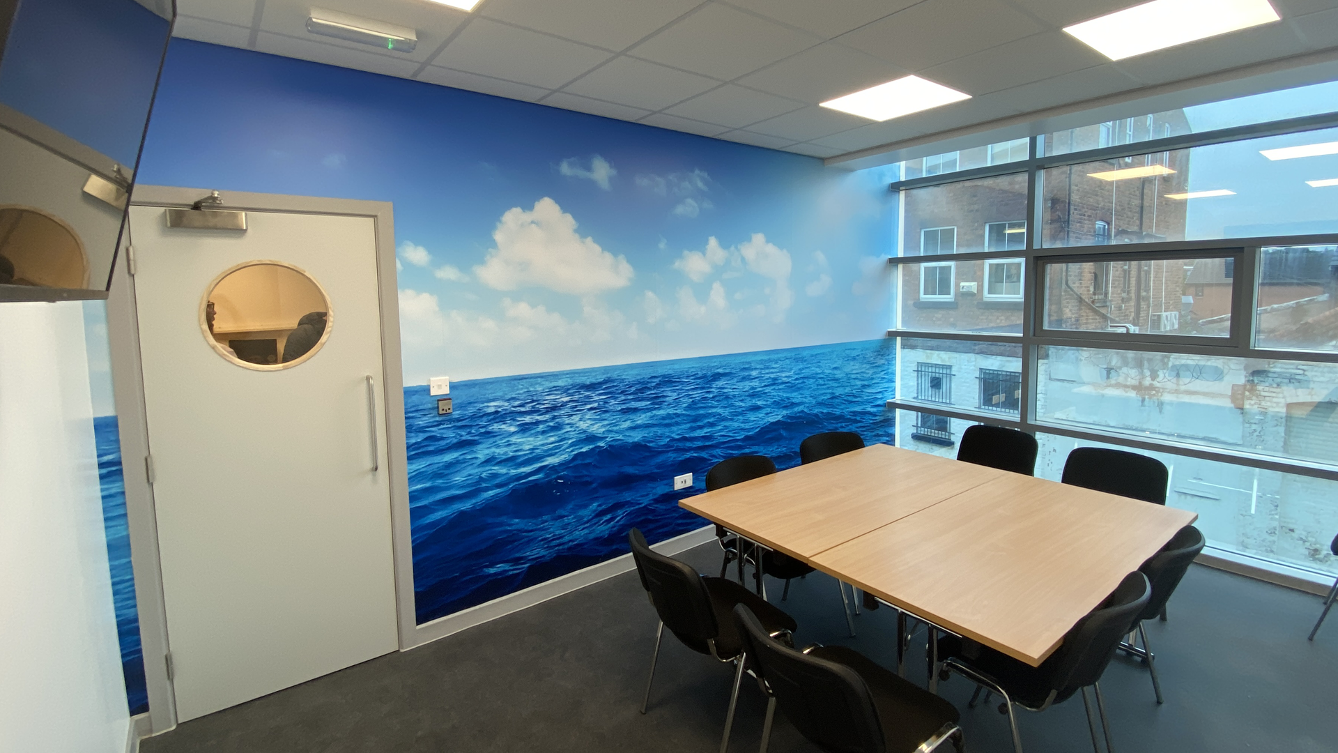 A meeting room at the Wirral hub with a table, chairs and a TV screen