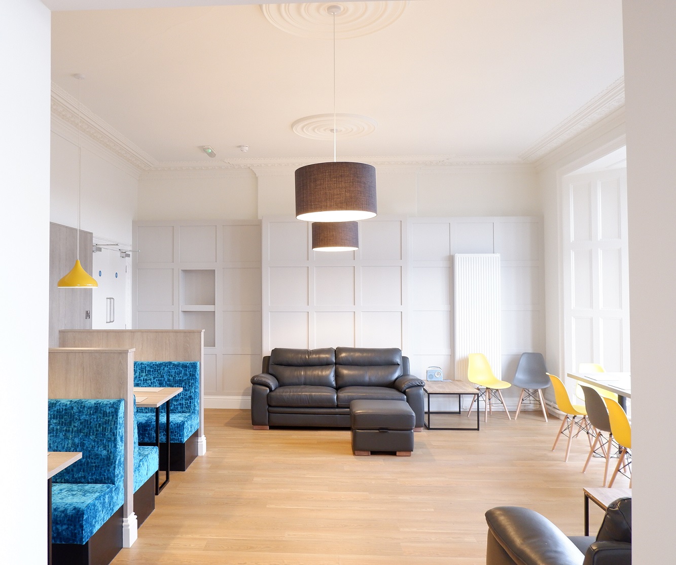 A group room with sofas, white walls and wooden floors