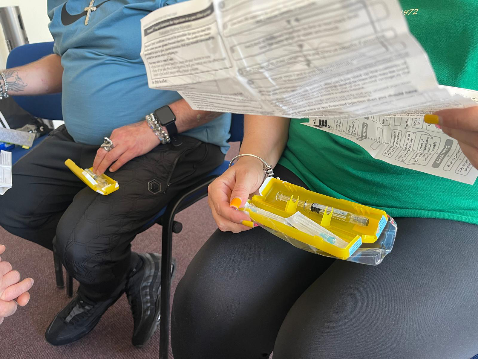 A yellow naloxone box is being held by a woman and the instructions are in her other hand