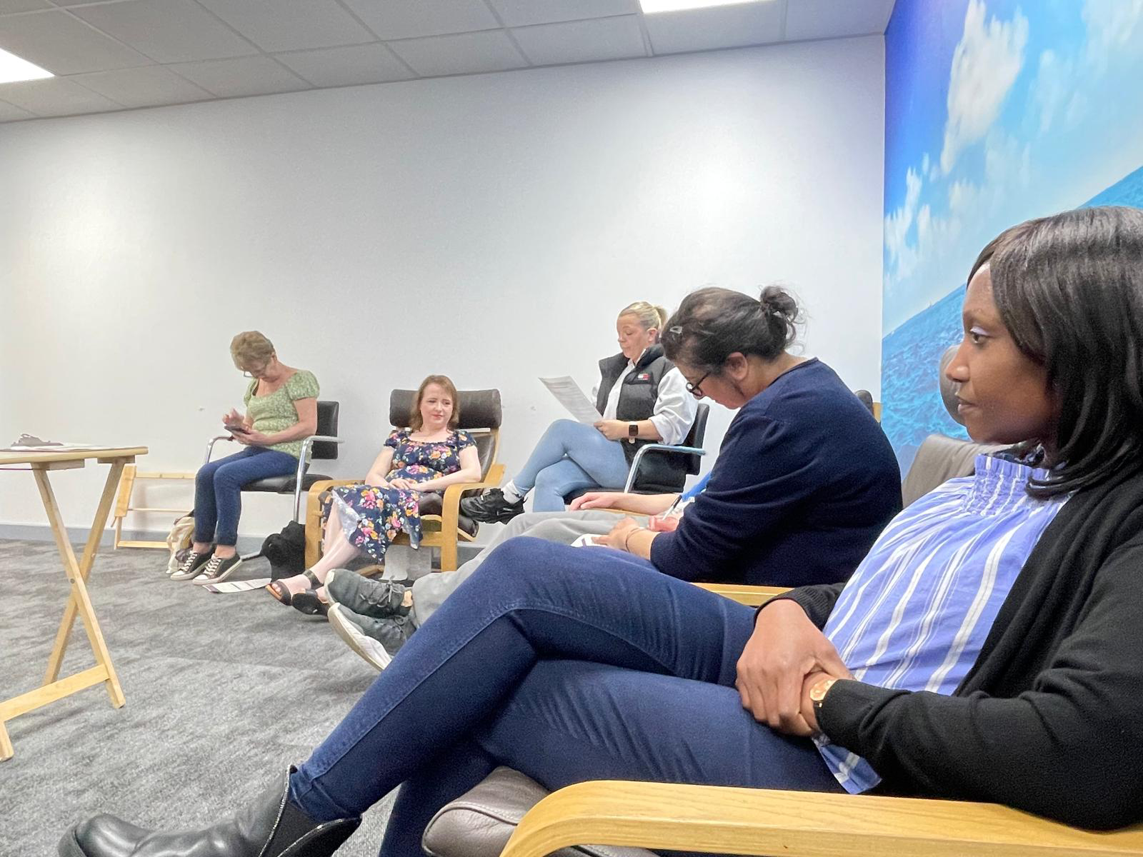 People sat around the edge of a room taking notes