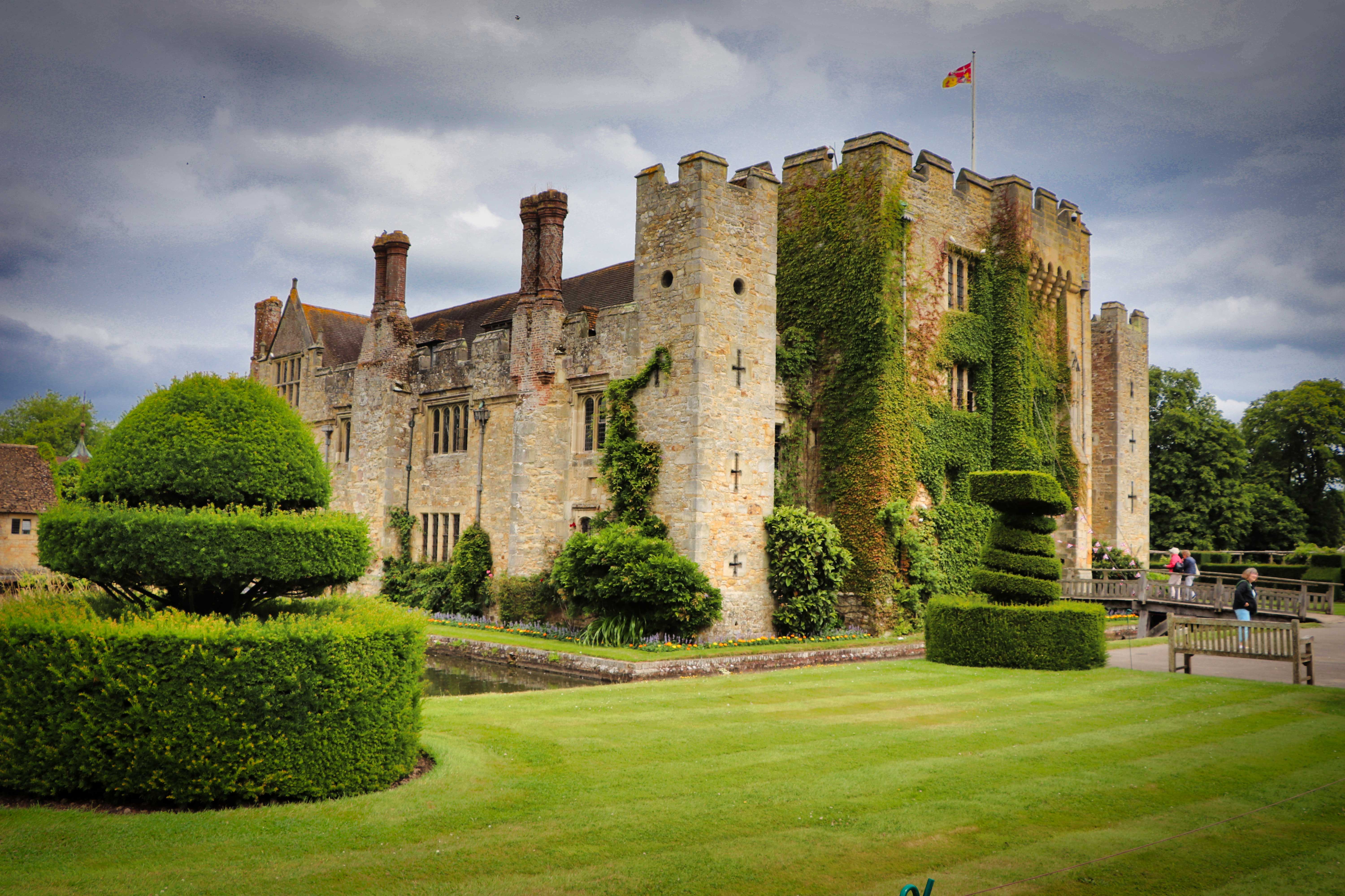 An old castle with bushes, trees and lawns that are well maintained