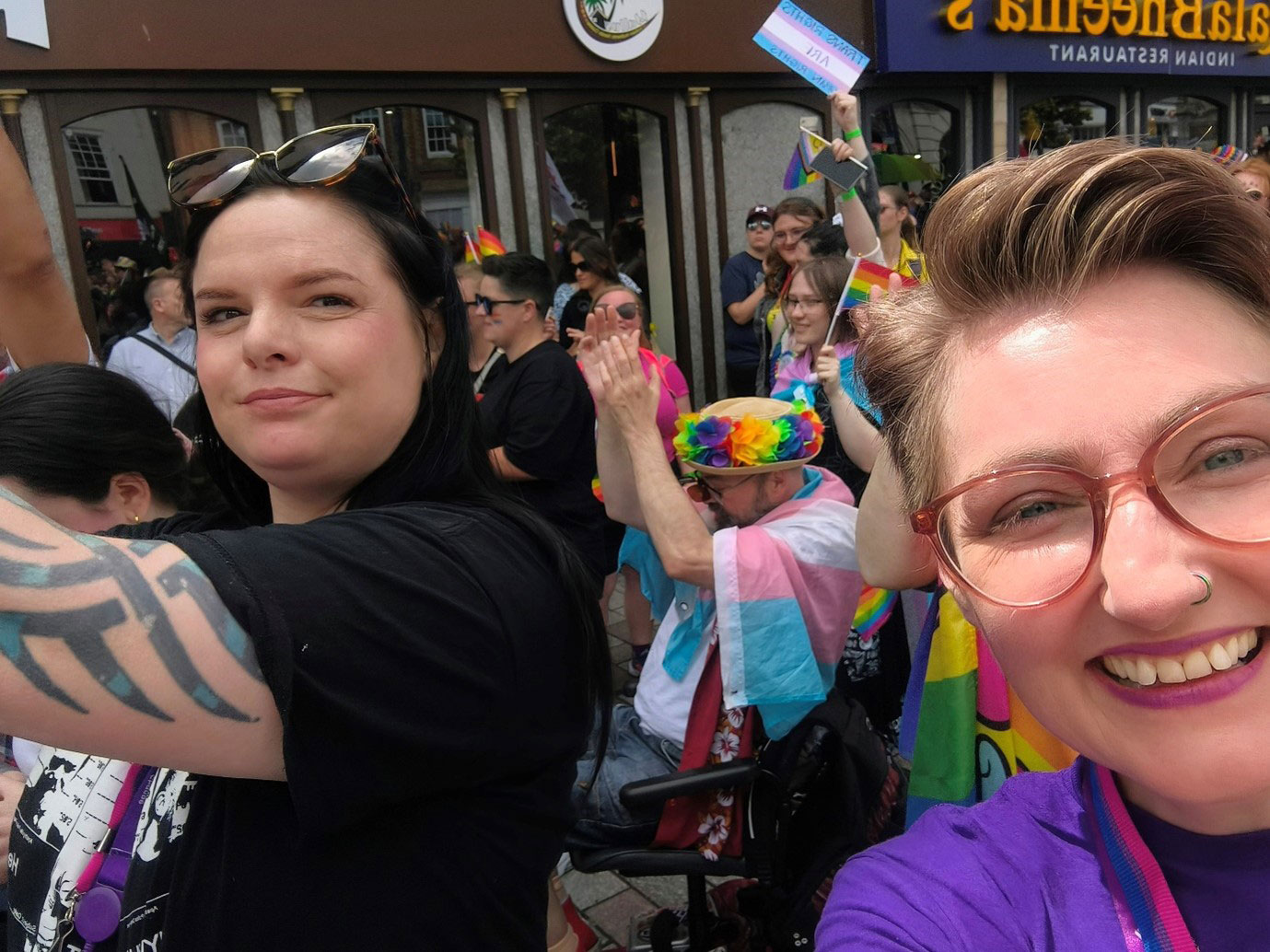 Bonnie has short cropped hair and is taking a selfie with a women who has black hair and is wearing all black