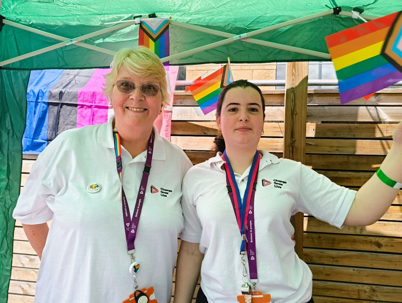 Two women stood under a gazebo wearing white t-shirts and purple lanyards