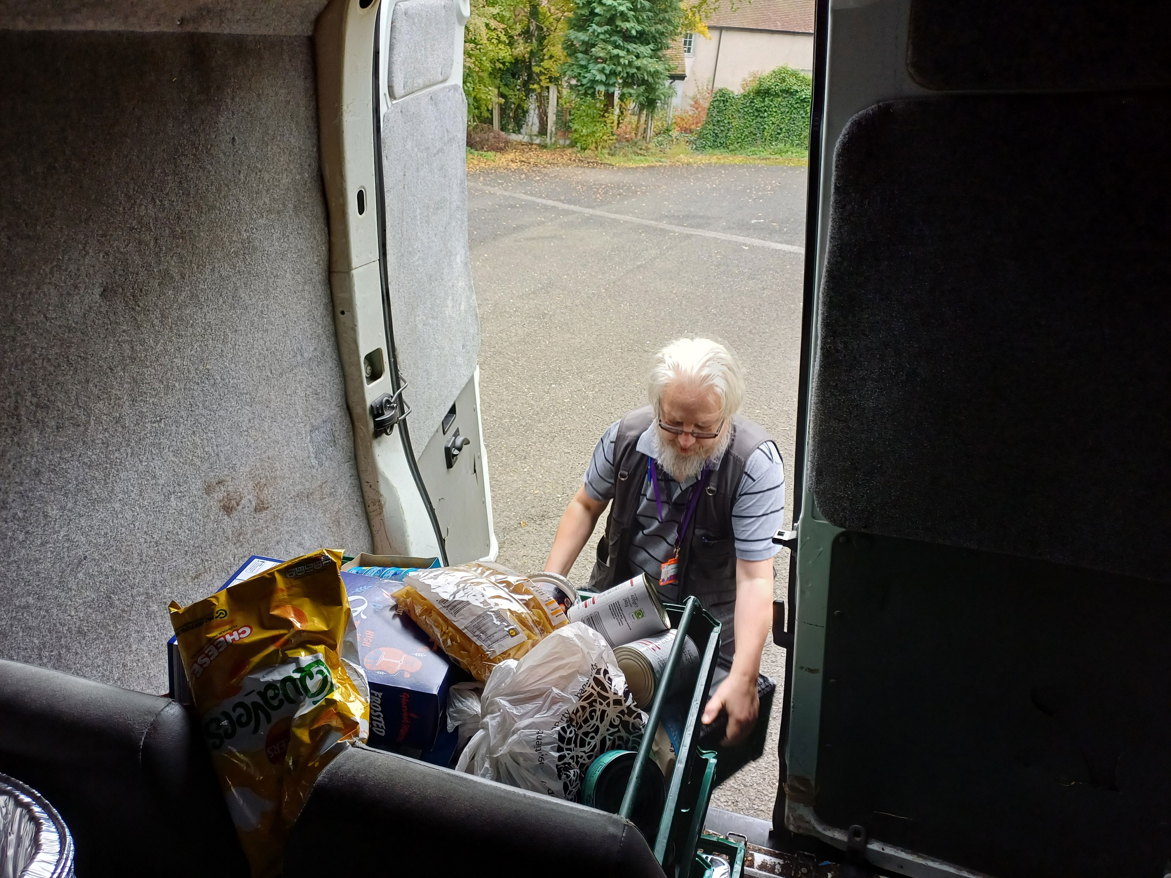 A man getting boxes of food out of the back of a van