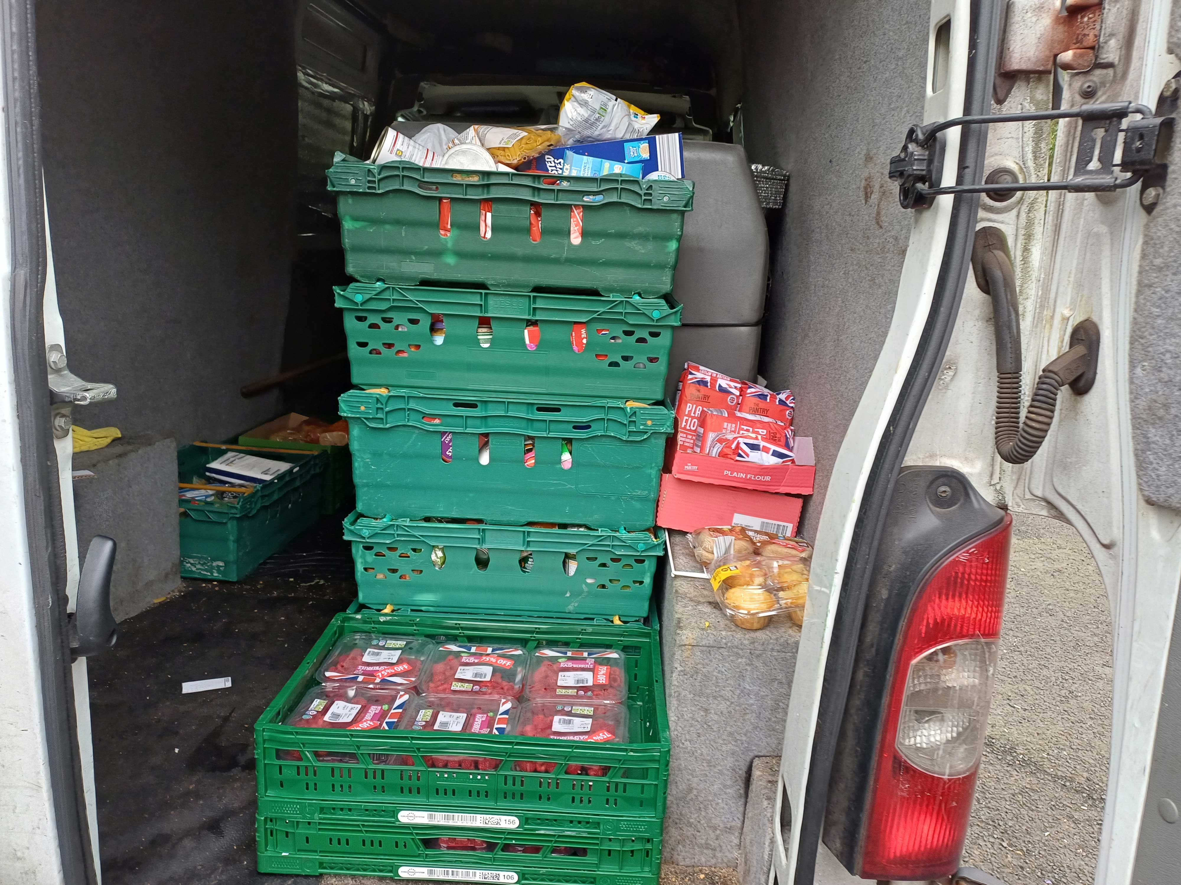 A stack of green crates full of food in the back of a van