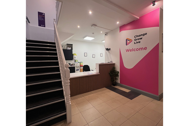 A reception area with stairs to the left hand side of the desk