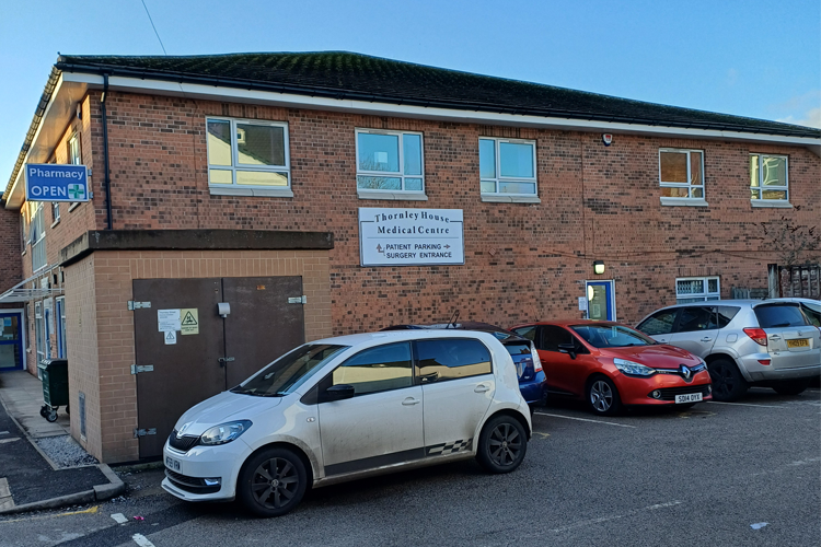 The outside of a brick building with signs above the door of Change Grow Live and cars parked on the street infront