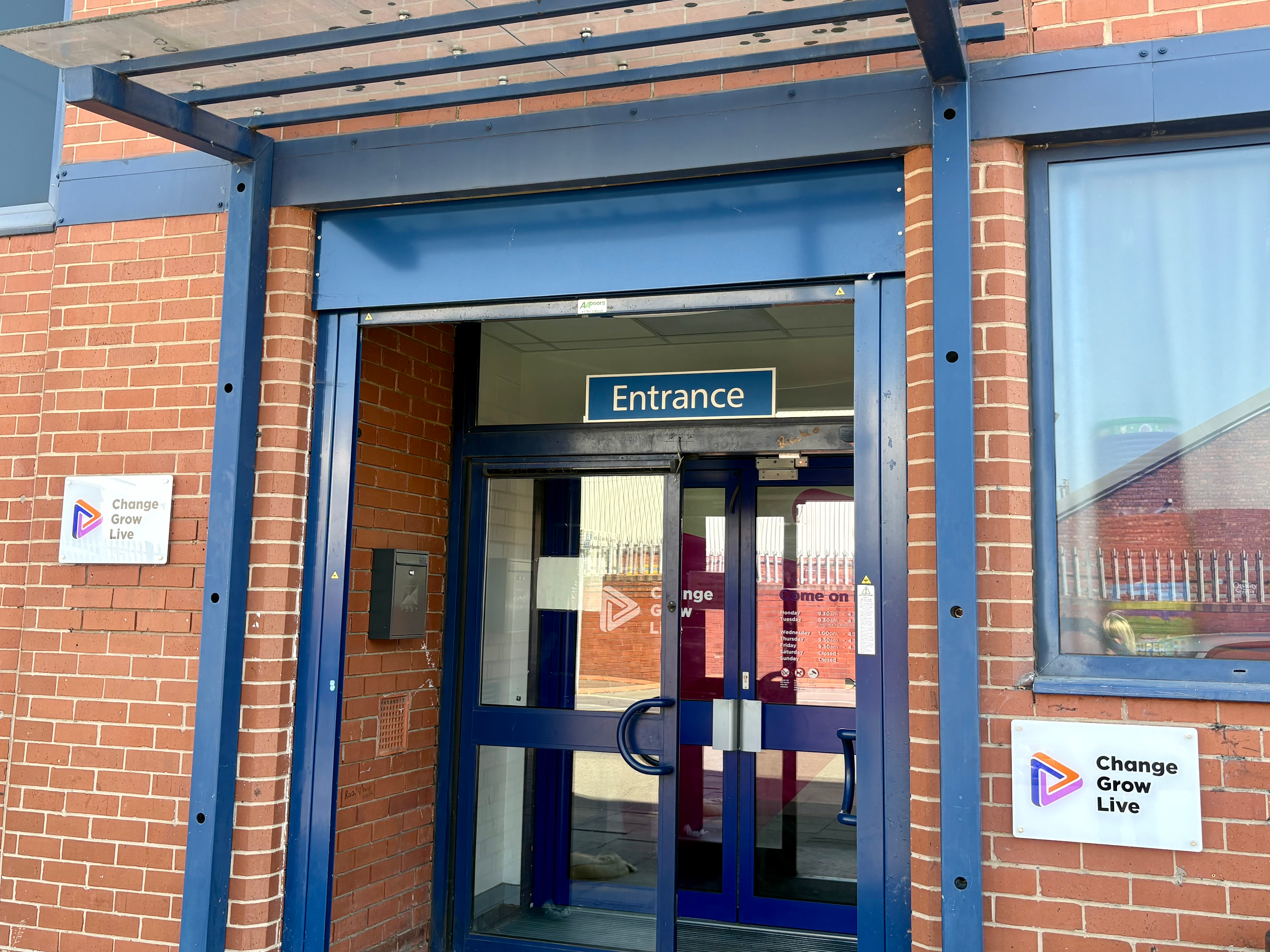 The entrance to a brick building, with a blue, metal porch cover
