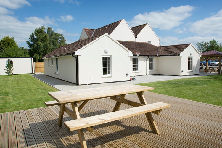 A spacious garden area with decking and a picnic table