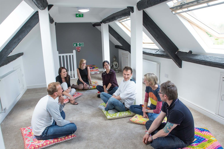 A group of people sat on the floor in a circle having a discussion