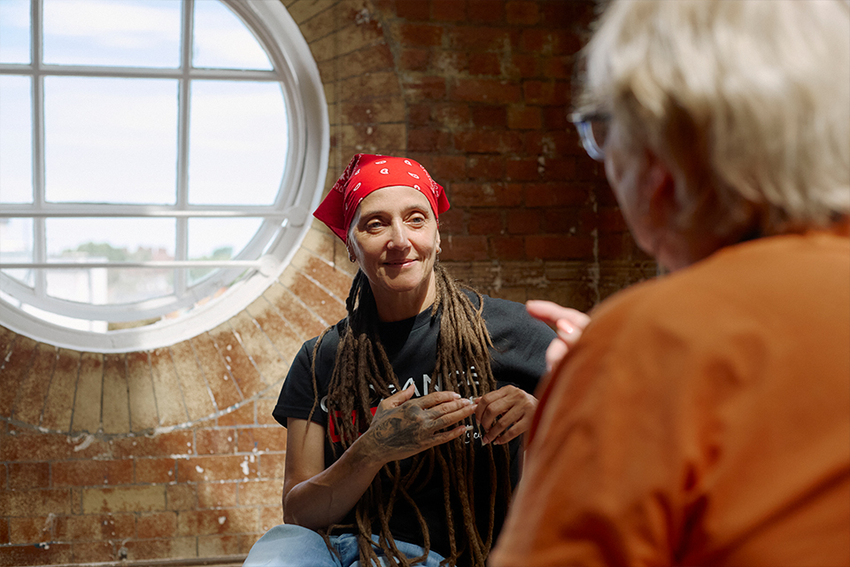 Two Change Grow Live colleagues having a gentle conversation in a room with exposed brick