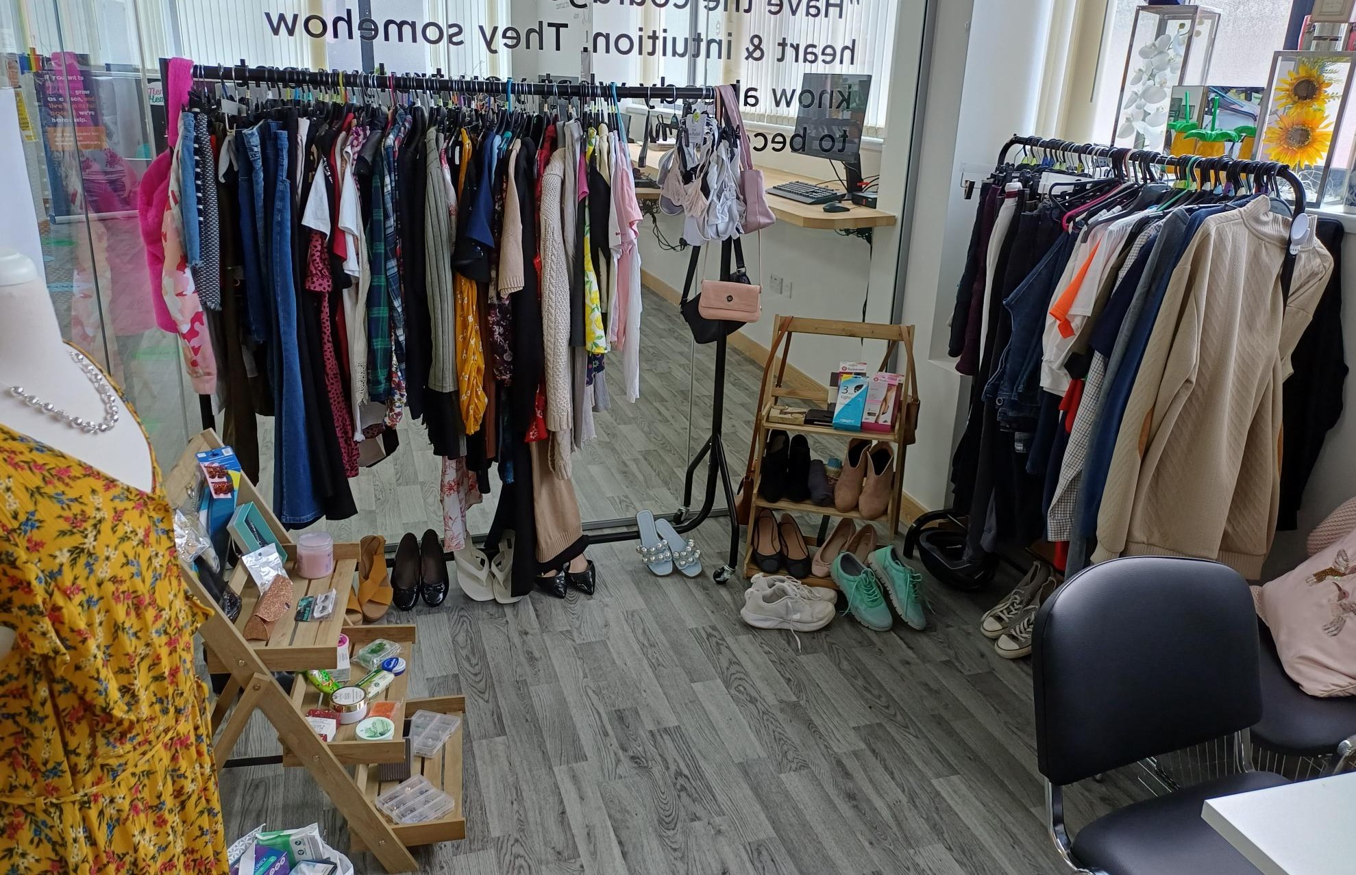 Clothes hang on rains and shoes and toiletries are displayed on shelves inside The Boutique