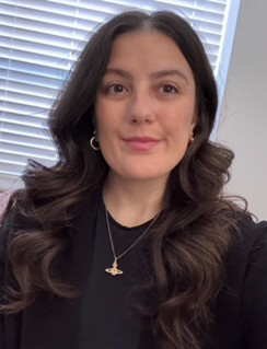 Christina has long dark hair and is smiling at the camera