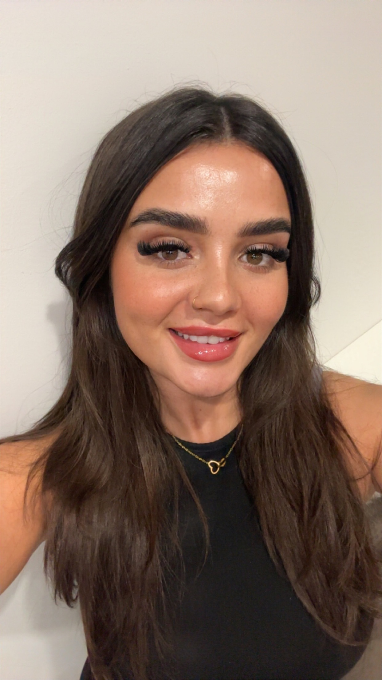 Hannah has long dark hair and is wearing a black vest. 