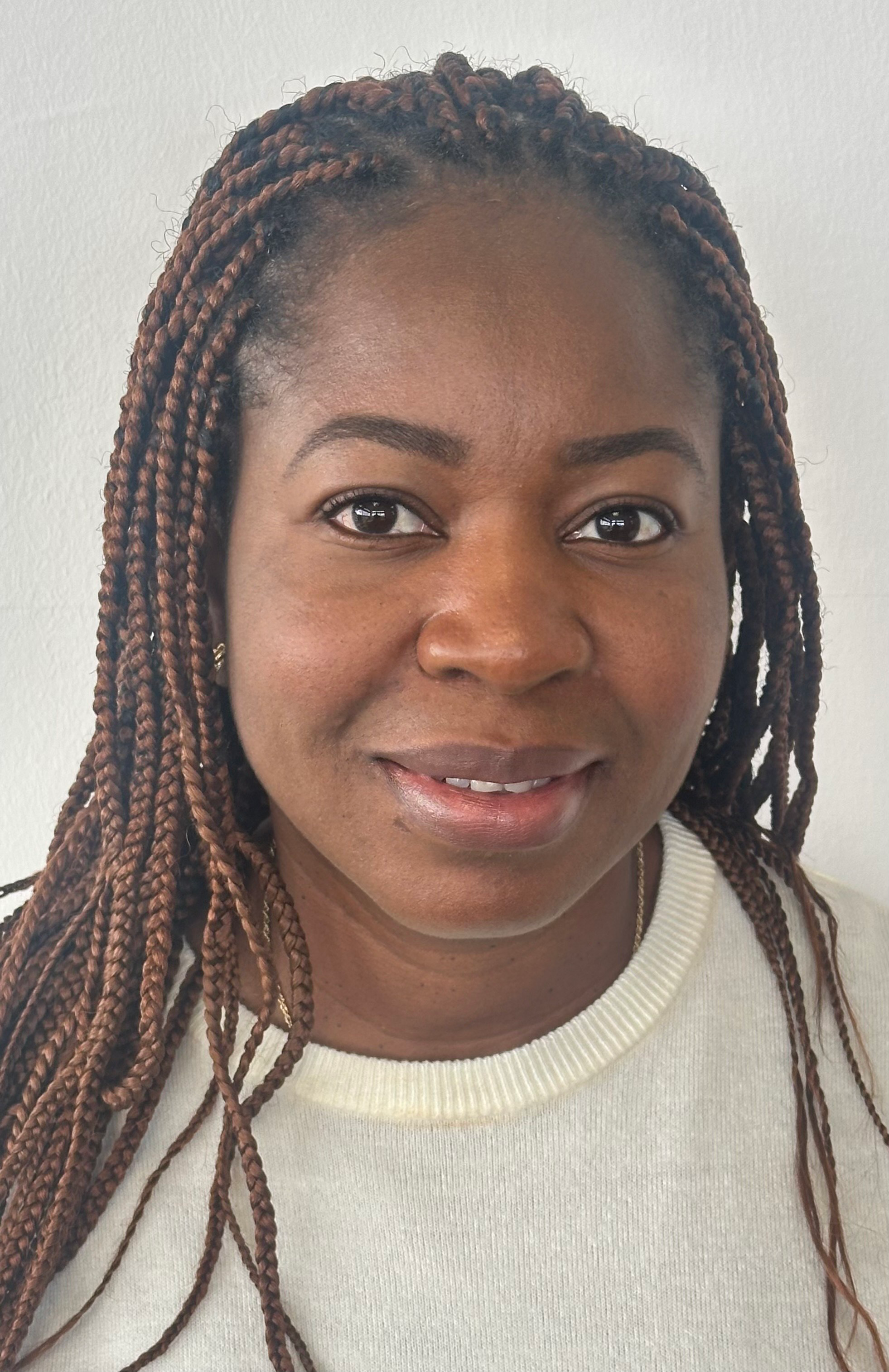 A young black woman with braids and a white t-shirt smiling at the camera