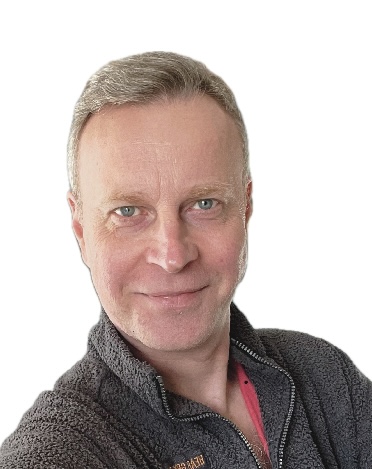 A man standing side on and looking at the camera over his shoulder. 