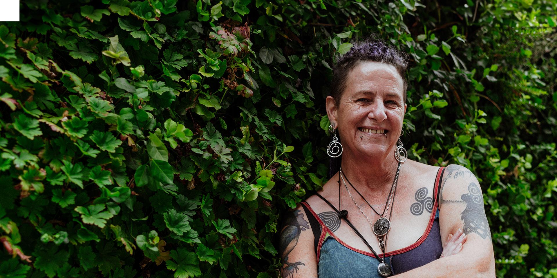 A person smiling at the camera with lot's of foliage in the background