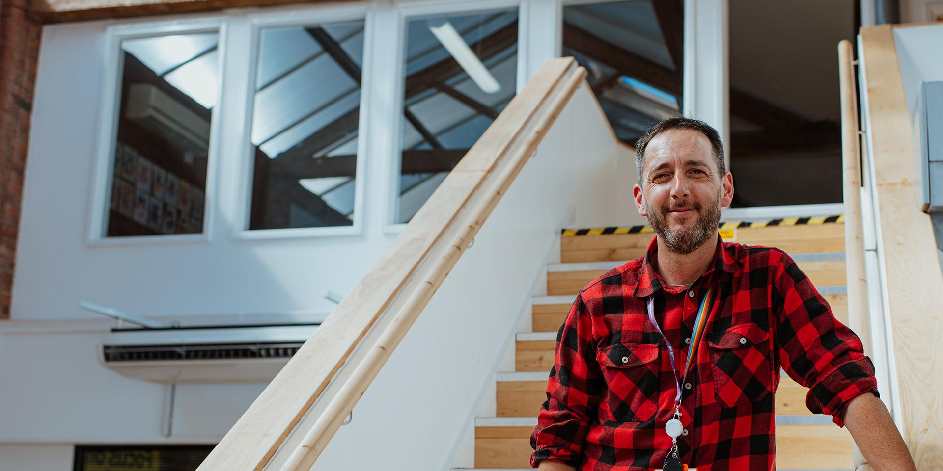 A person smiling at the camera standing on the stairs