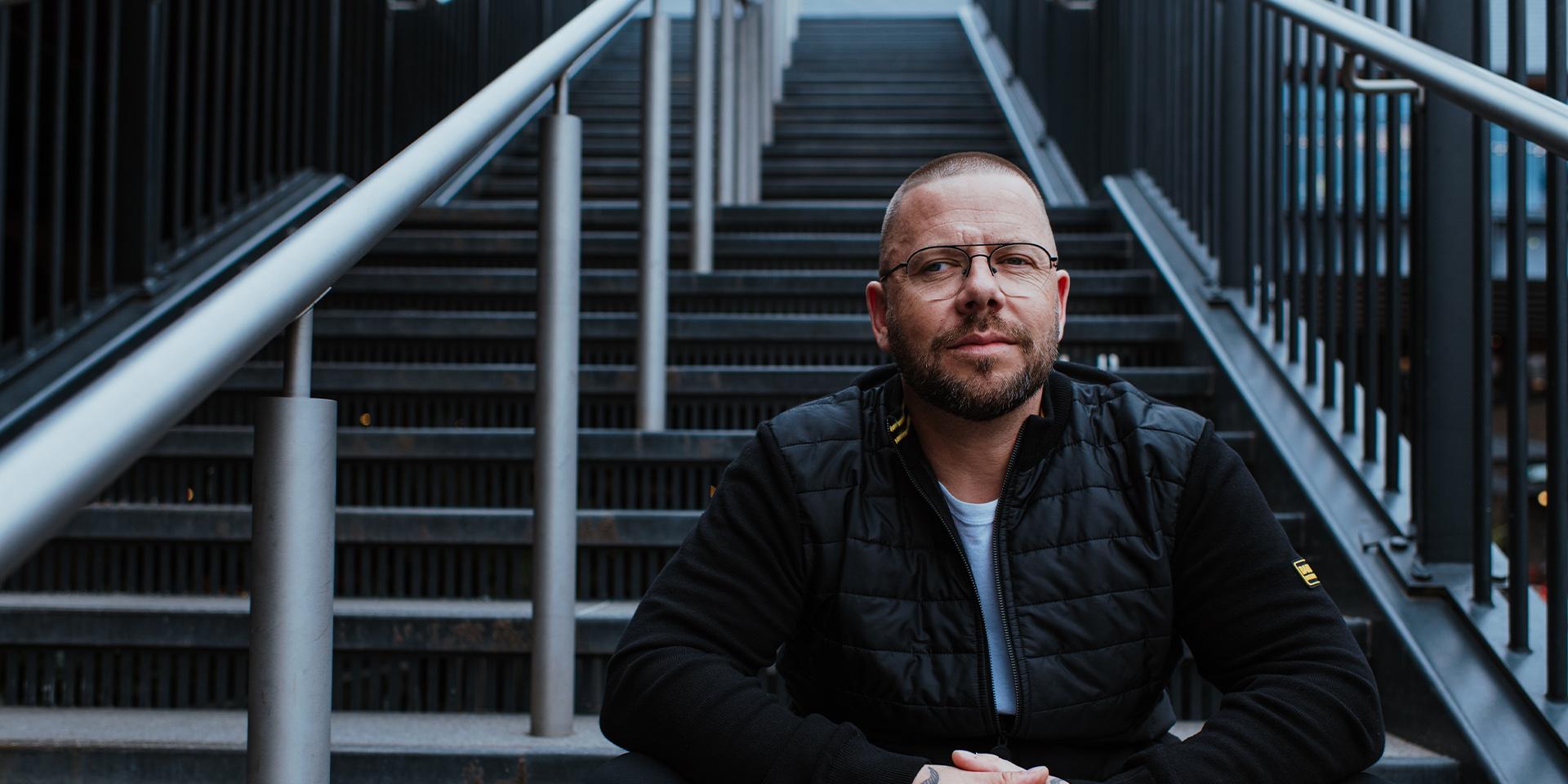 A person sat on stairs outside looking at the camera pensively