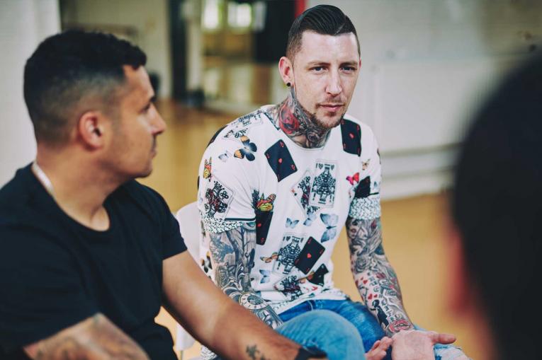 Two men sitting talking in a group