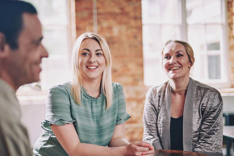 Three people are sitting together smiling