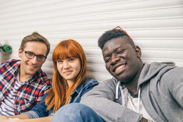 Three young people smiling and looking at camera