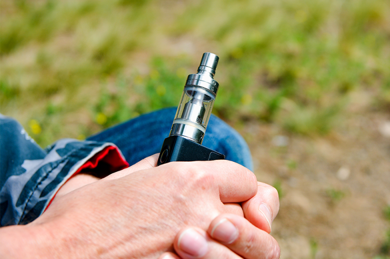 A close up image of a hand holding a vape