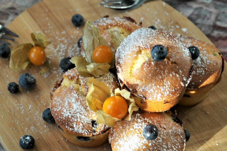 A wooden chopping board with blueberry muffins on