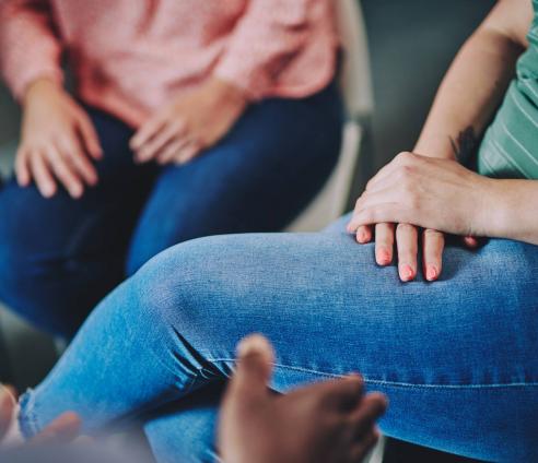 A woman has her hands folded on her lap