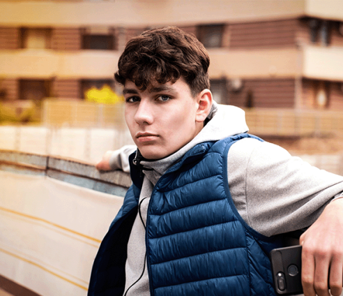 a young man in an urban housing setting looking solemnly direct to camera 