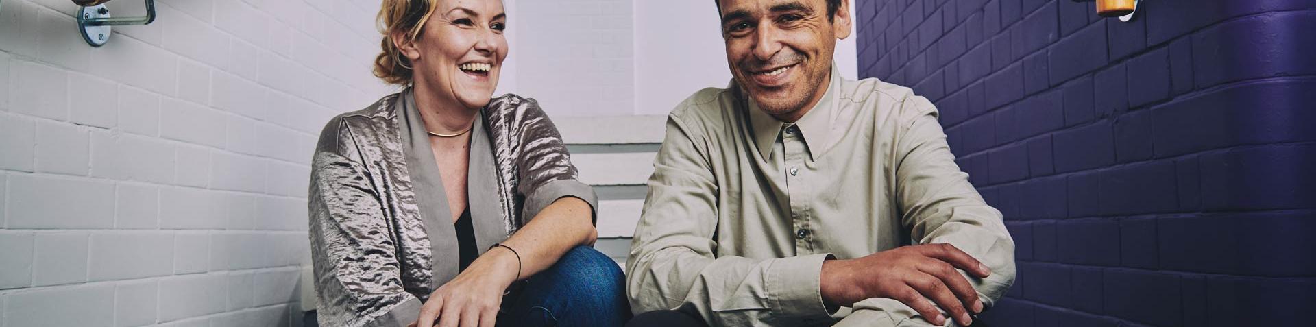 a woman and a man sitting on the stairs laughing