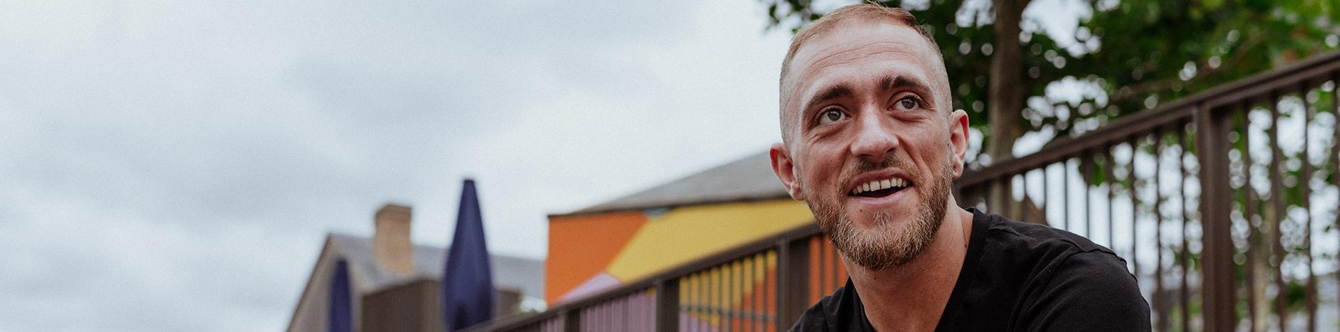 A person looking off to the side sat outside