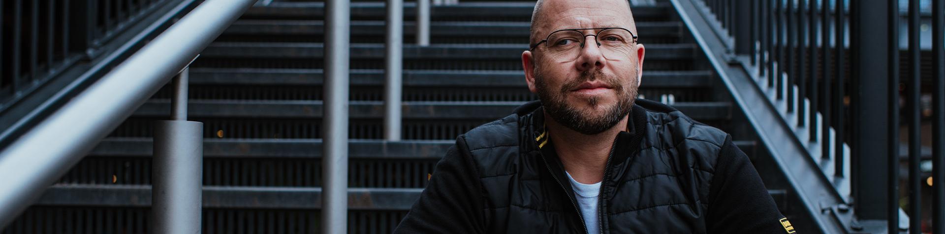A person sat on stairs outside looking at the camera pensively