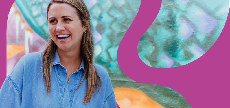 a person laughing in a friendly manner in front of a teal street mural