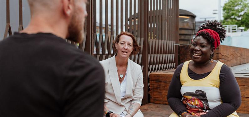 Three people talking to each other, one with their back to the camera