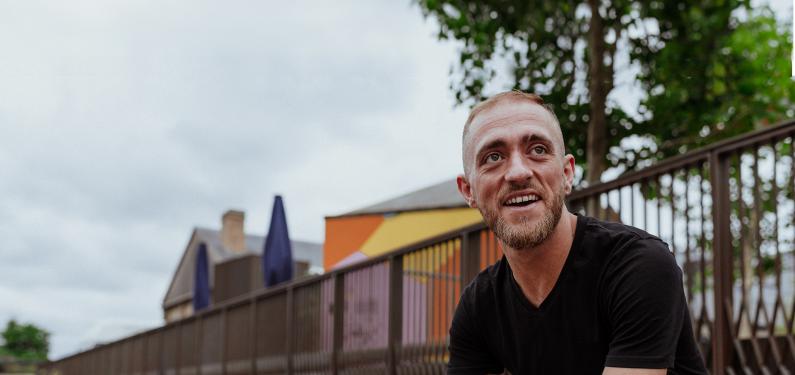 A person looking off to the side sat outside