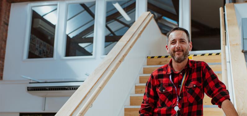 A person smiling at the camera standing on the stairs