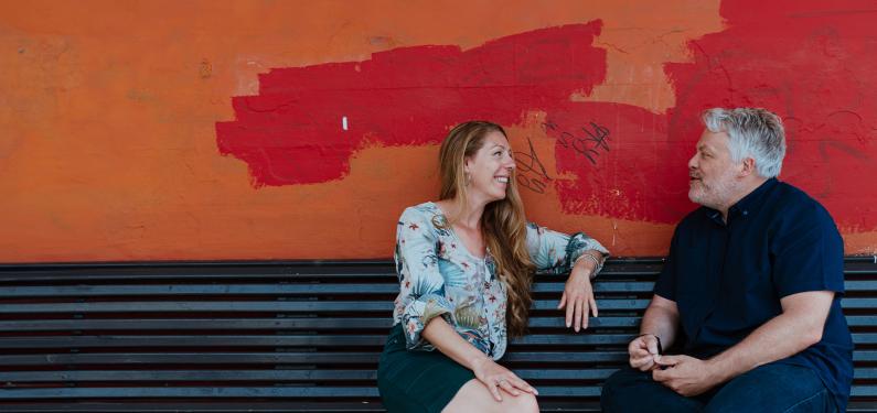 Two people talking on a bench