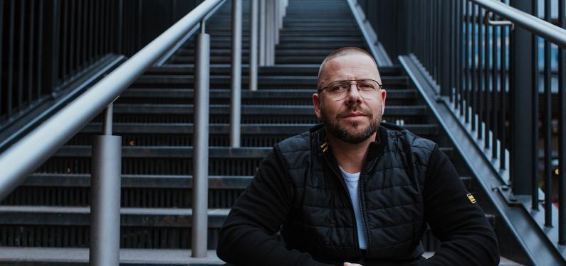 A person sat on stairs outside looking at the camera pensively
